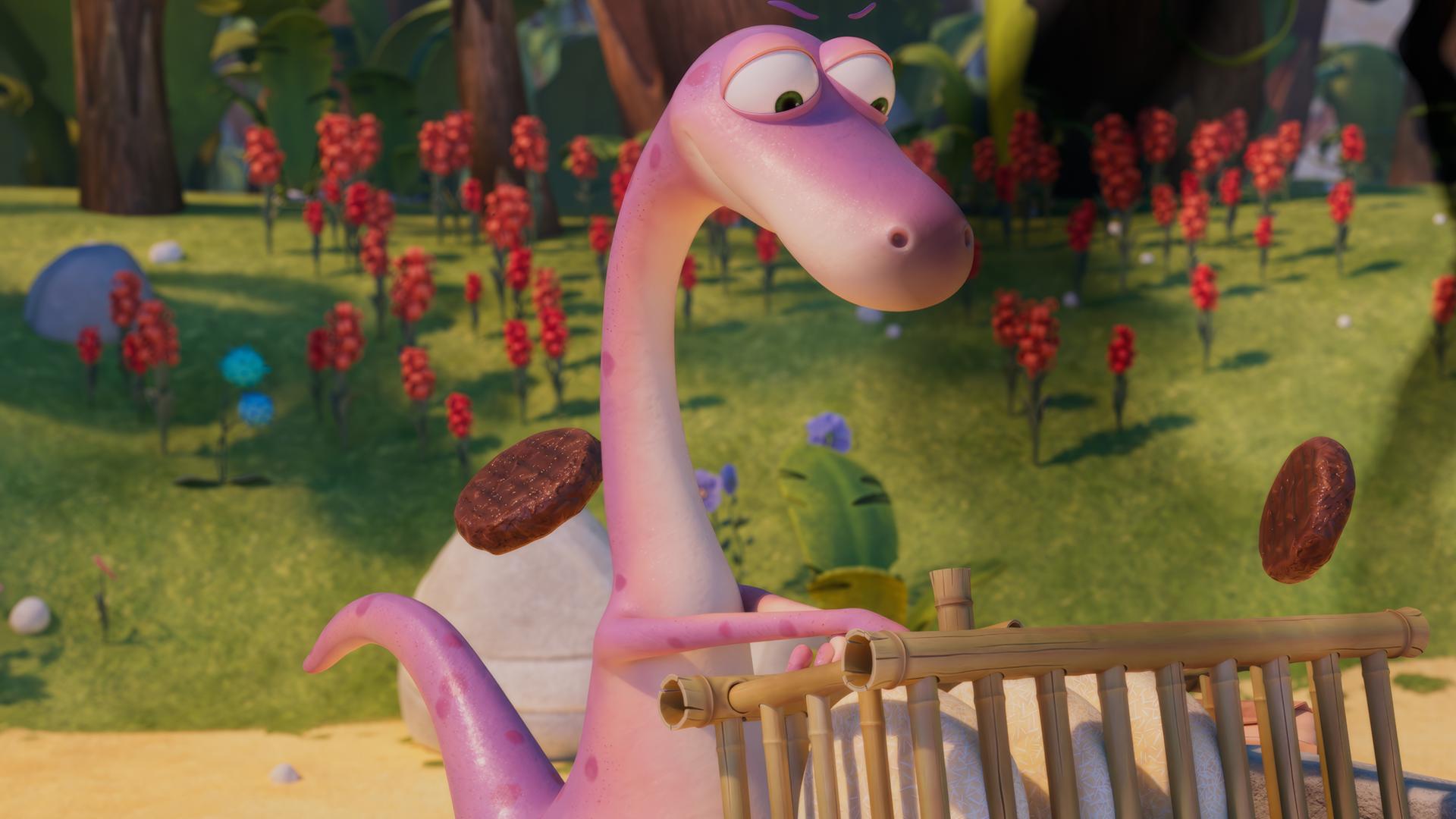 Minus Drei, der rosafarbene Dinosaurier, steht an einer steinernen Fritteuse und versucht, Burger zu frittieren. Dabei fliegen Burger-Bratlinge durch die Luft. Minus Drei schaut angestrengt.