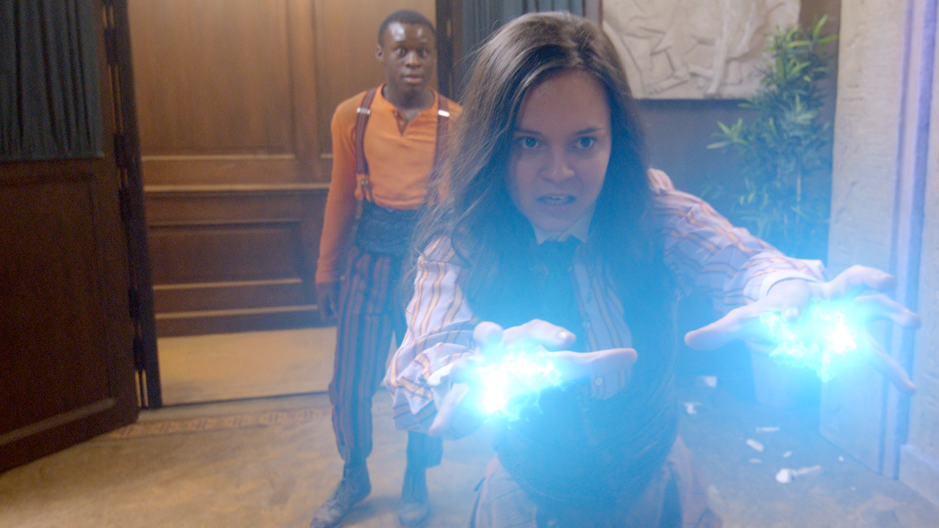 Will steht überrascht hinter Theo, die mit ausgestreckten Händen ihre Magie in Form von blauen Blitzen ihrem Feind entgegenschleudert.