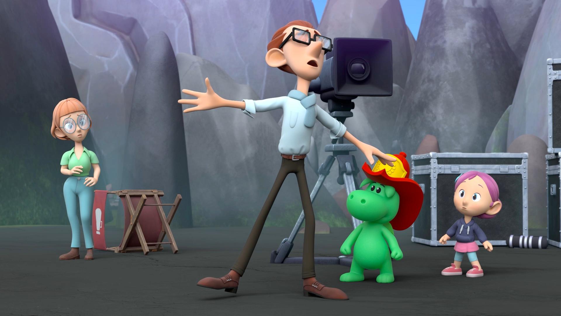 Grisu mit seinem roten Feuerwehrhelm, Stella und der Filmregisseur Ratatino stehen an einem Filmset. Im Hintergrund steht eine große Filmkamera auf einem Stativ. Ratatino macht eine verzweifelte Geste.