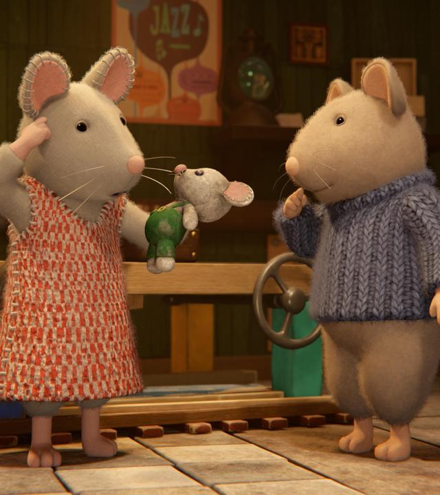 Julia und Sam stehen im Keller zwischen Regalen und Kisten. Julia hält eine kleine Stoffmaus in der linken Hand und greift sich mit der rechten Hand an die Stirn. Sam hat die rechte Hand fragend vor die Lippen gelegt. Beide schauen verwundert auf das Stofftier.