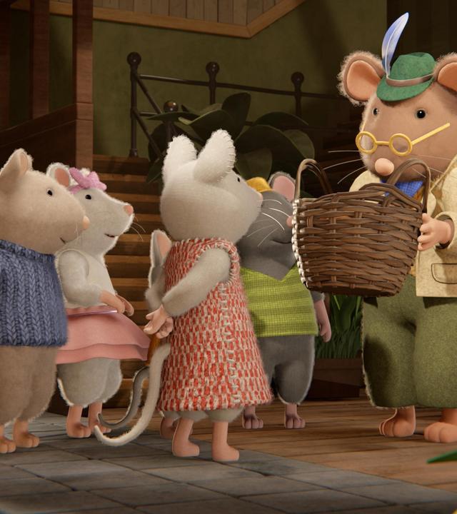 Im Eingangsbereich des Mäusehauses steht Herr Grummel mit einem geflochtenen Korb mit Käsesternen in den Händen und erklärt etwas. Um ihn herum stehen im Halbkreis Sam, Ella, Julia und Tonio und lauschen ihm aufmerksam.