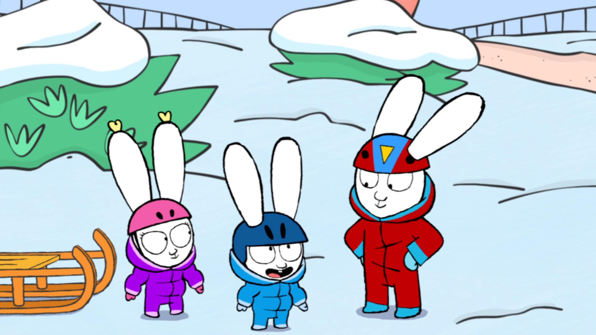 Franz, Simon und Alice stehen gemeinsam im Schnee. Alle drei tragen Schneeanzüge und Helme auf dem Kopf. Alice steht neben einem Schlitten.