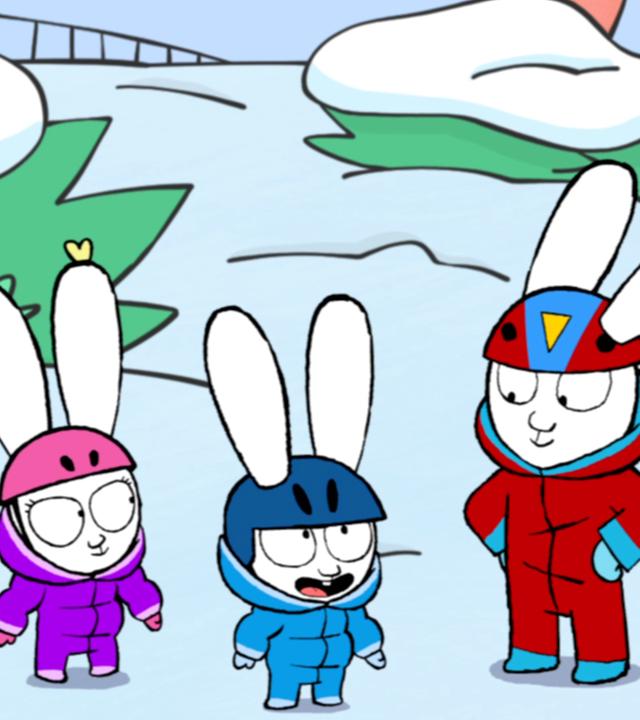 Franz, Simon und Alice stehen gemeinsam im Schnee. Alle drei tragen Schneeanzüge und Helme auf dem Kopf. Alice steht neben einem Schlitten.