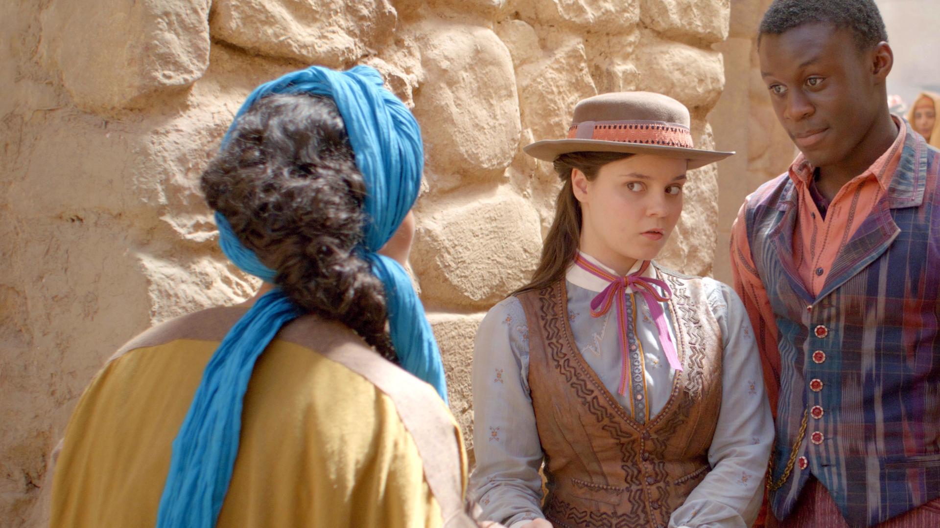 Theo und Will sind in Ägypten auf der Spur des magischen Artefakts. Auf einem Bazar treffen sie eine Informantin. Theo schaut skeptisch, Will dagegen optimistisch.