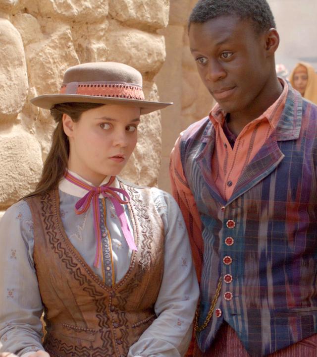 Theo und Will sind in Ägypten auf der Spur des magischen Artefakts. Auf einem Bazar treffen sie eine Informantin. Theo schaut skeptisch, Will dagegen optimistisch.