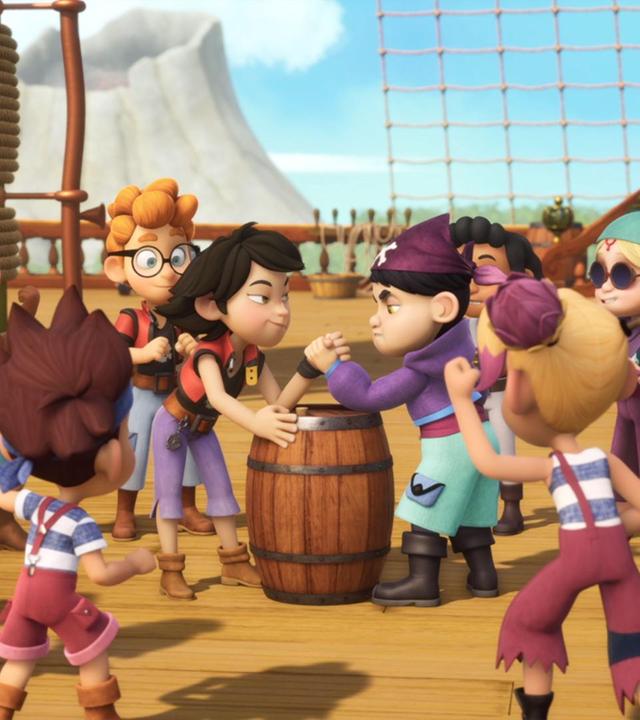 Zoe und Raul messen ihre Stärke beim Armdrücken auf einem Holzfass. Alle Piratenschüler stehen drumherum und feuern sie an.