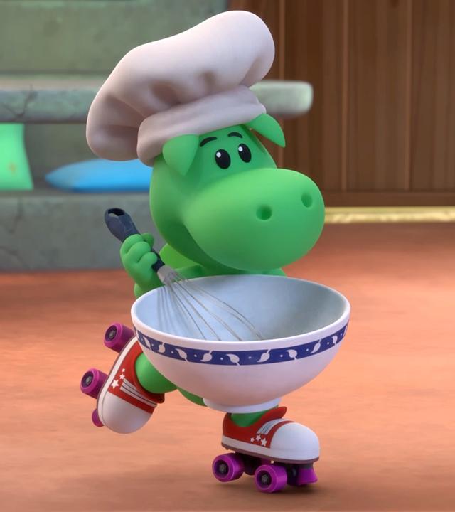 Grisu, der kleine, grüne Drache, trägt eine Kochmütze. In den Händen hält er eine Schüssel und einen Schneebesen. Er fährt auf Rollschuhen durch sein Zimmer.