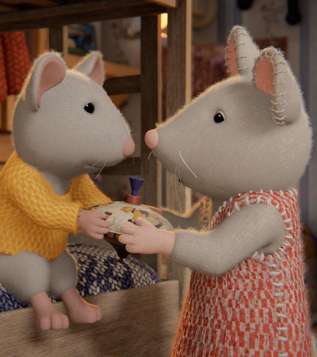 Ben sitzt im Kinderzimmer auf dem unteren Bett eines Stockbettes und überreicht Julia, die vor ihm steht, einen Spielzeugkreisel. Beide schauen einander an.