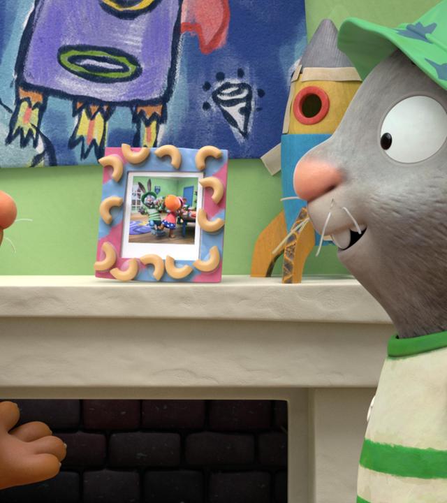 Die beiden besten Freunde Posy, die Maus und Pip, das Kaninchen stehen sich vor dem Kamin gegenüber. Sie tragen lustige Sommerhüte, aus denen oben ihre Ohren hervorschauen. Auf dem Kaminsims steht ein Foto von ihnen in einem selbst gebastelten Bilderrahmen.