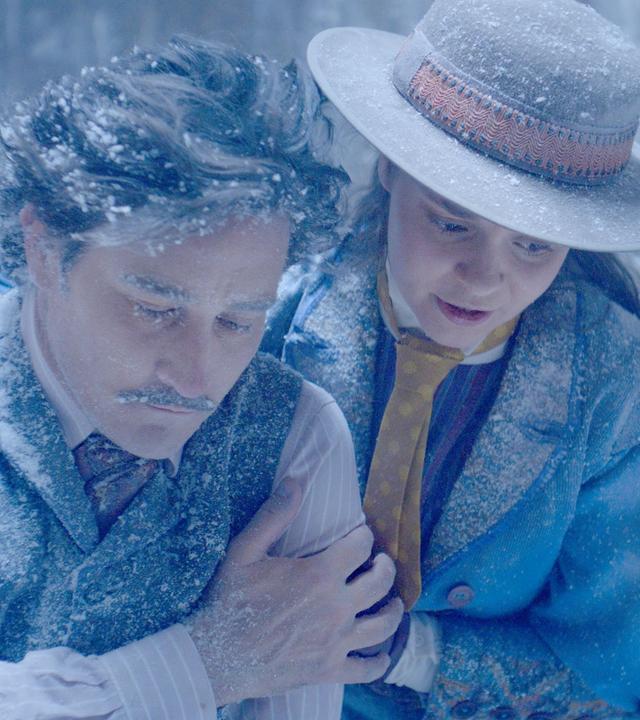 In einer alten Ruine mit Hieroglyphen an den Wänden, legt Theodosia ihrem erschöpften Vater Alistair den Arm um die Schultern. Alles ist voller Eis und beide sehen erschöpft und fast erfroren aus.