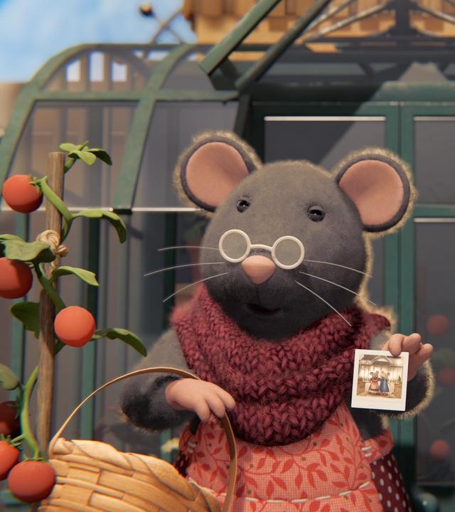 Oma Gouda und ihre alte Freundin stehen nebeneinander vor dem Gewächshaus auf der Terrasse des Mäusehauses. Oma Gouda trägt im rechten Arm einen Korb, ihre Freundin stützt sich auf einen Stock. Beide tragen Brillen und schauen zufrieden nach vorne.