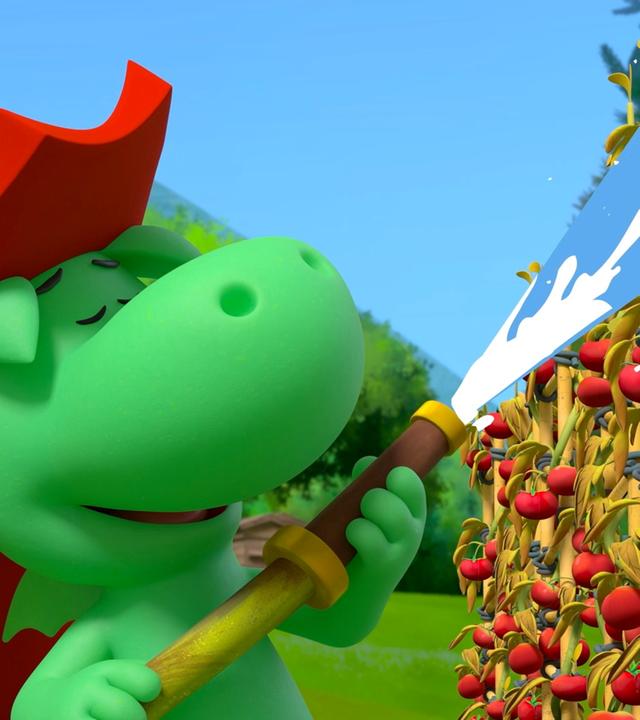 Grisu, der kleine, grüne Drache mit dem roten Feuerwehrhelm, spritzt mit einem Feuerwehrschlauch Tomaten mit Wasser nass. Er sieht dabei sehr glücklich aus und hat die Augen geschlossen.