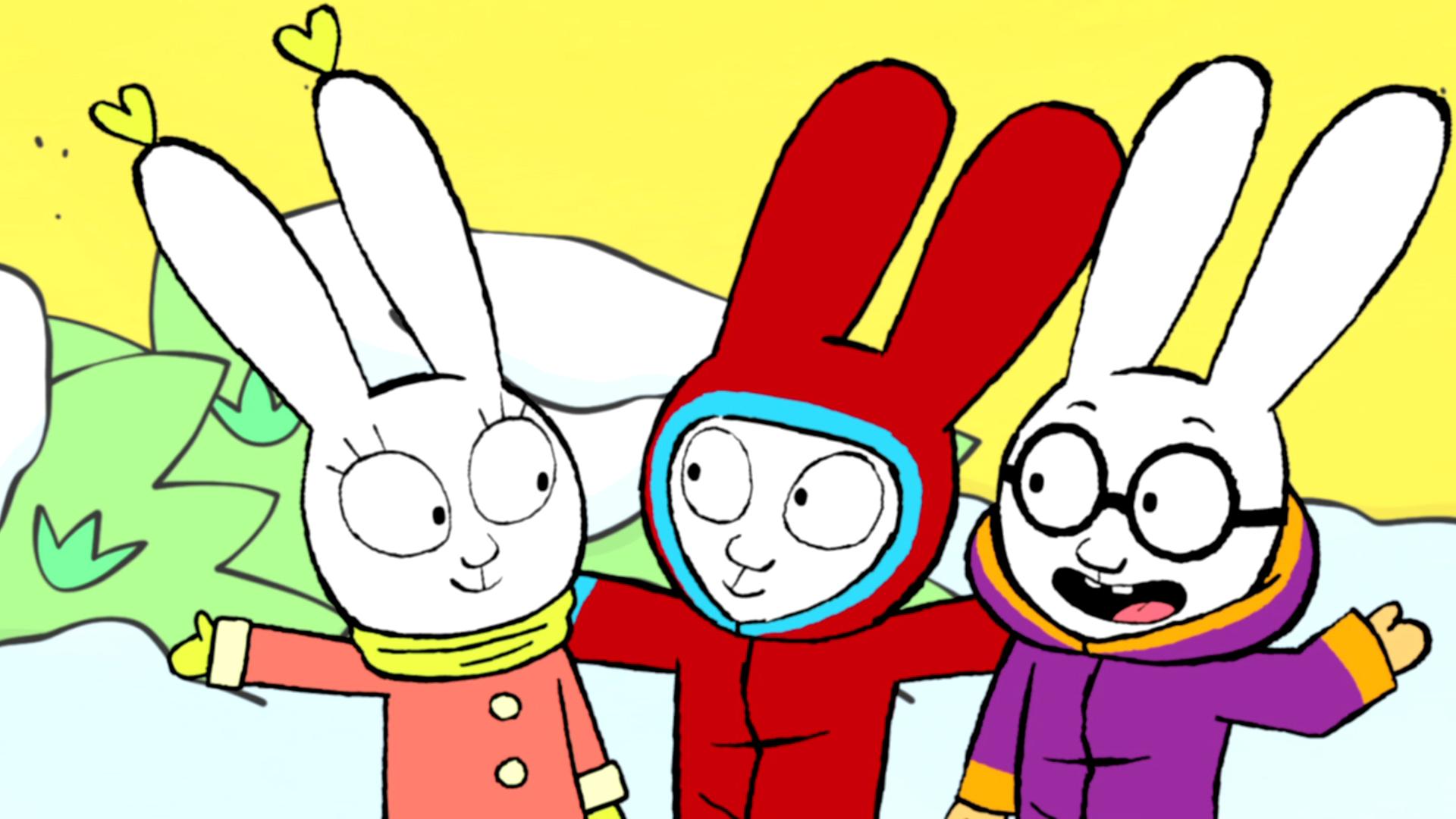 Lou, Simon und Ferdinand stehen auf dem verschneiten Pausenhof. Alle drei tragen dicke Winterjacken und Lou hat zusätzlich zwei herzförmige Ohrringe an. Simon steht in der Mitte und streckt seine Arme nach rechts und links aus, um Lou auf seiner rechten Seite und Ferdinand auf seiner linken Seite zu umarmen. Die drei Freunde lachen gemeinsam und strahlen sich an.