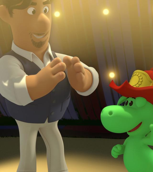 Der kleine, grüne Drache mit dem roten Feuerwehrhelm steht zusammen mit dem Opernsänger Maestro Stranavoce in einem mit Glühbirnen schön beleuchteten Zirkuszelt.