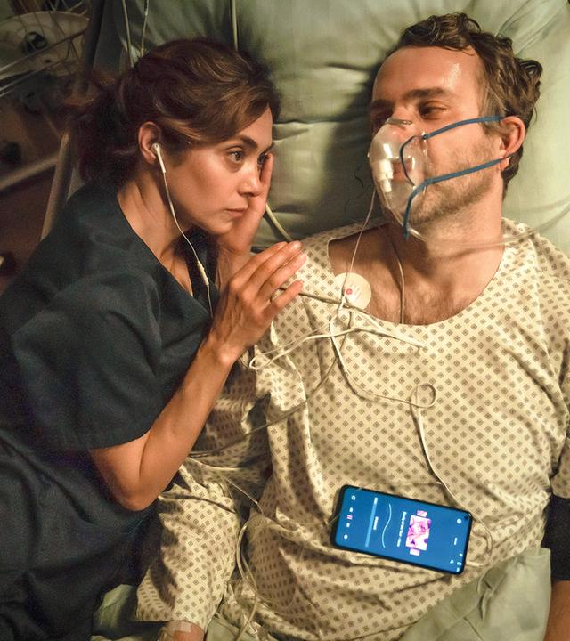 Dr. Barbara Forster (Julia Richter) liegt neben dem im Sterben liegenden Feuerwehrmann Christian (Stefan Rudolf) im Krankenhausbett. Er trägt eine Atemmaske, beide haben je einen Kopfhörer im Ohr.