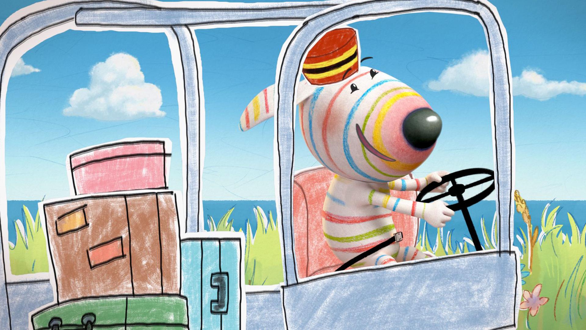 Hund Dylan sitzt freudig fahrend in einem Transportshuttle. Er trägt einen Pagenhut und hinter ihm liegen drei große bunte Koffer sowie eine Schachtel im Shuttle.