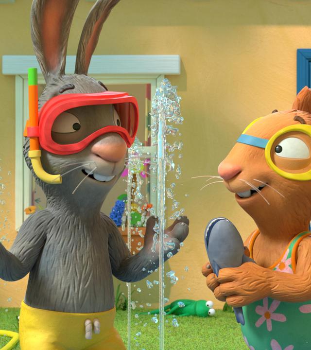 Im Garten vor dem Haus spielen die allerbesten Freunde Pip, das Kaninchen und Posy, die Maus. Wasserfontänen sprudeln bis hoch zu ihren Köpfen. Pip trägt eine Badehose und eine Taucherbrille mit Schnorchel, Posy einen Badeanzug und Schwimmbrille. Sie hat einen Spielzeughai in den Händen und blickt lachend zu Pip.