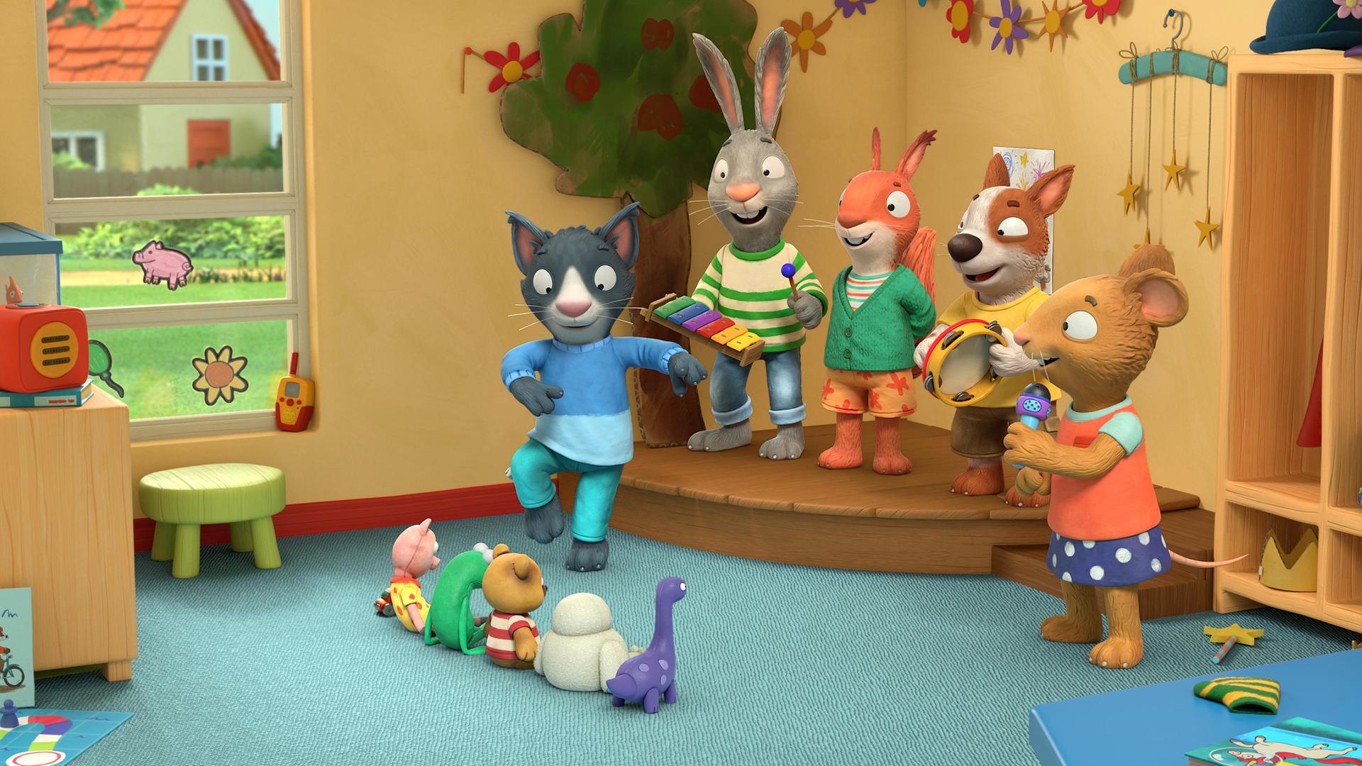 Im Haus auf der Bühne in der Ecke des Spielzimmers: Die Freunde spielen als Band zusammen und Kater Mo tanzt ausgelassen auf dem Teppich davor. Das Kaninchen Pip spielt Xylophon, das Eichhörnchen Jamila lächelt, der Hund Zac schlägt im Takt auf ein Tamburin und die Maus Posy hält ein Mikrofon in der Hand. Als Zuschauer sitzen Stofftiere in einer Reihe auf dem Teppich vor der Bühne.