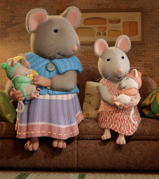 Im Wohnzimmer sitzen Sams Mutter und Julia nebeneinander auf der Couch im Wohnzimmer. Sams Mutter hält ihre zwei kleinen schlafenden Babys im rechten Arm und auch Julia hat ein Baby im Arm, das sich an sie ankuschelt und schläft.