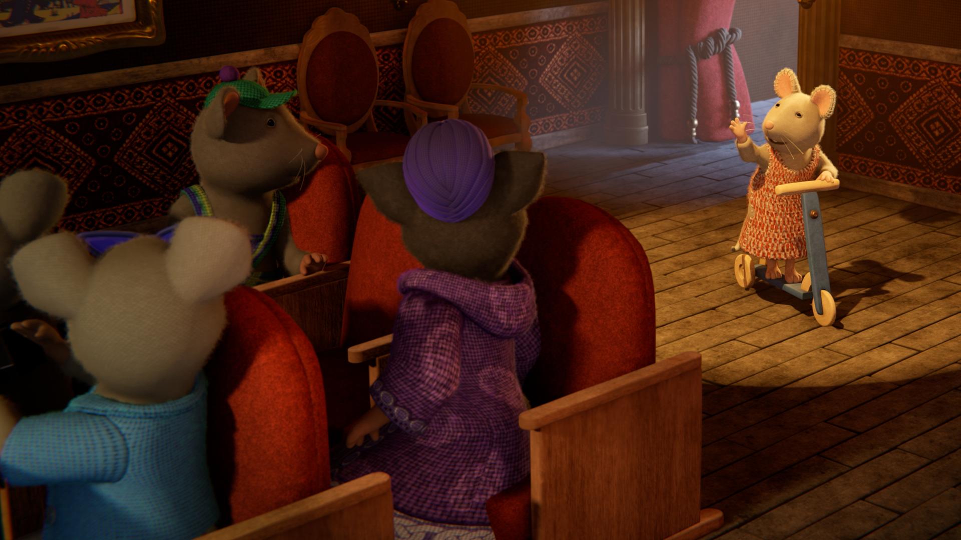 Julia steht mit ihrem Roller auf der Theaterbühne im Scheinwerferlicht und hebt grüßend den Arm. Das Publikum schaut auf sie.