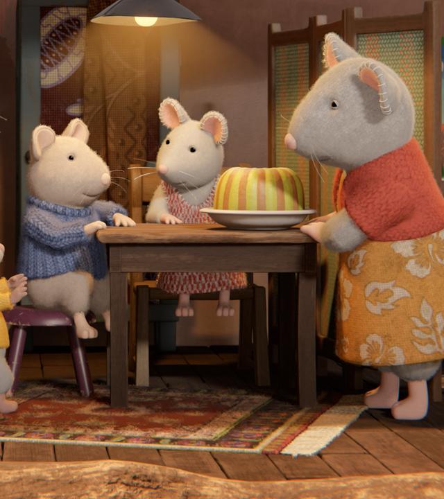 Julias Mutter stellt den fertigen Kuchen auf den Küchentisch. Sam und Julia sitzen bereits auf Stühlen am Tisch und freuen sich auf den Pandan-Kuchen. Die Nachbarn stehen erwartungsvoll links vom Tisch.