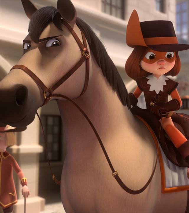 D'Artagnan sitzt auf ihrem Pferd und schaut gebannt zu Alex, der mit erschrockenem Blick neben ihr steht. Er hält eine Brioche in seiner rechten Hand. Im Hintergrund läuft ein Spaziergänger vor Häusern.