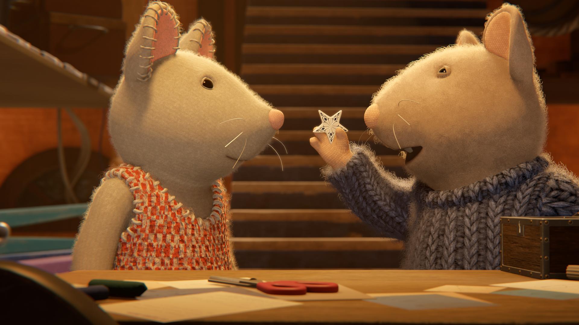 Sam und Julia stehen im Keller vor einem Tisch mit Bastelsachen. Sam hält mit der rechten Hand einen kleinen Stern aus Porzellan hoch und zeigt ihn Julia, die aufmerksam auf den Stern schaut.