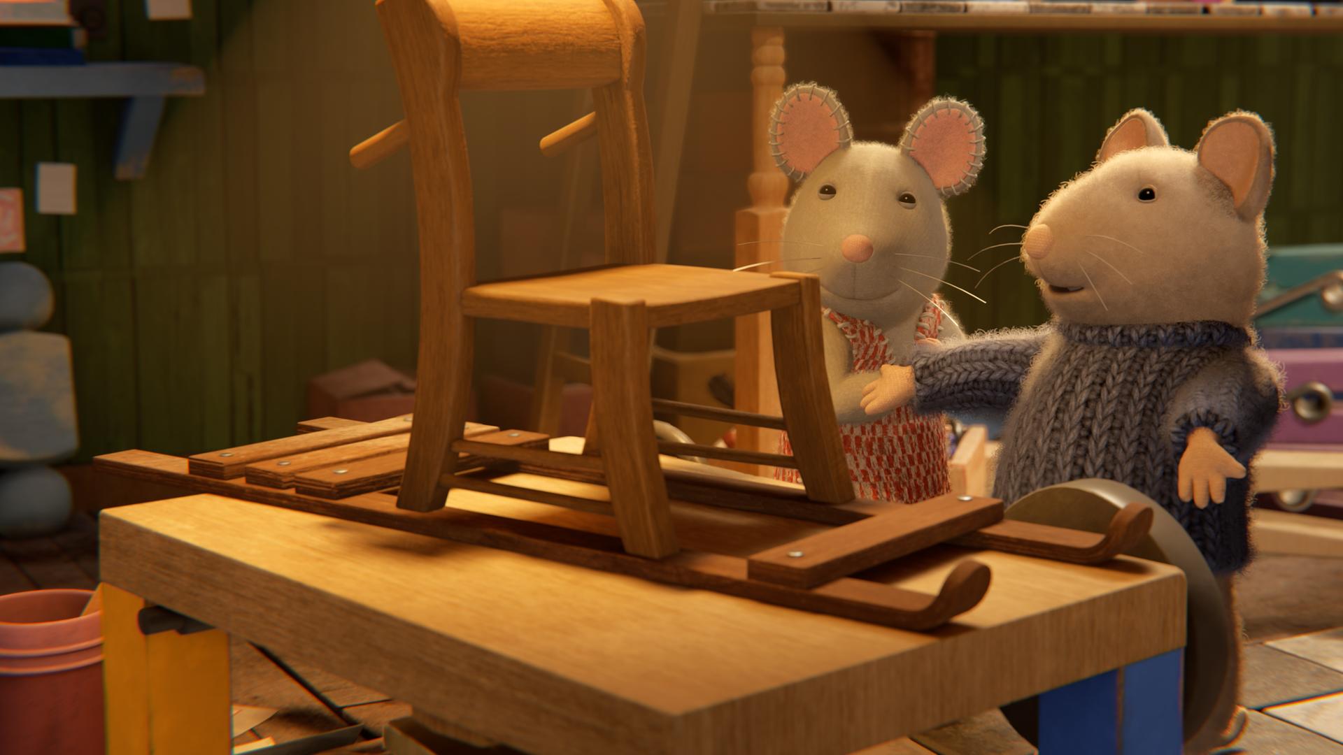 Sam und Julia stehen in einem Kellerraum vor einem Holztisch, auf dem ein selbstgebauter Holzschlitten steht. Sam und Julia schauen stolz auf den Schlitten, Sam präsentiert ihn dabei mit ausgebreiteten Armen.