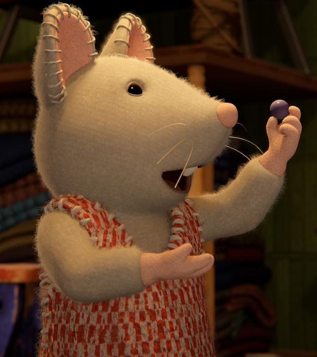 Julia steht in einem dunklen Keller und hält eine Murmel mit der linken Hand in die Höhe. Sie schaut erfreut auf die Murmel.