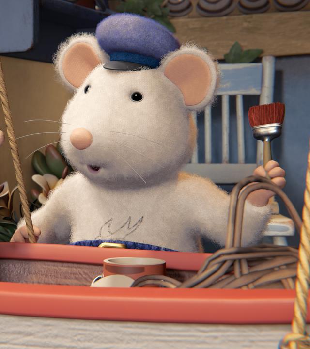 Opa Seemann steht vor einem Boot, das mit Seilen aufgehängt ist. Er wendet sich Sam und Julia zu, die hintereinander in dem Boot sitzen. 