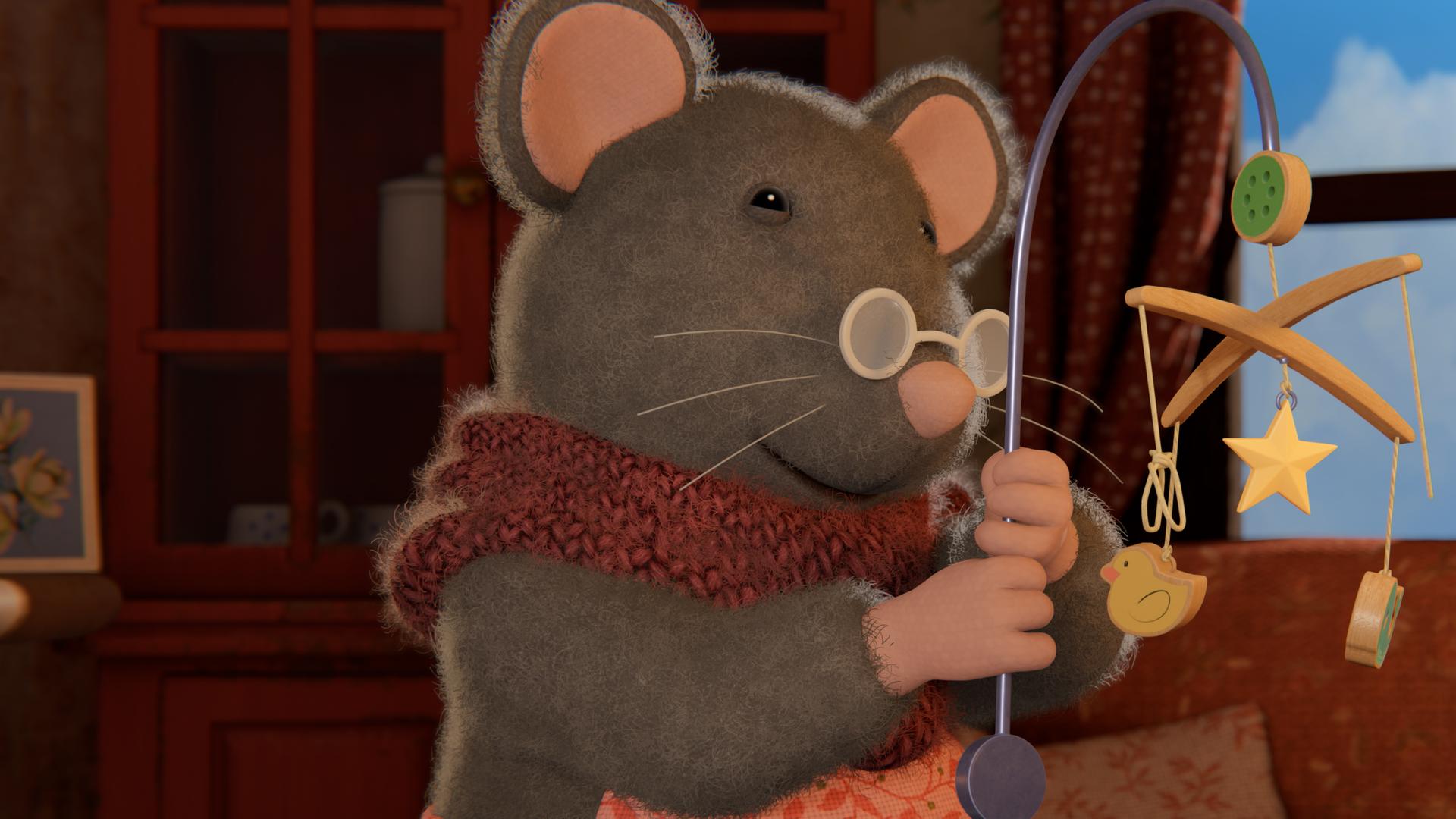 Oma Gouda hält mit beiden Händen das alte Mobile mit den vielen kleinen Holzteilchen in verschiedenen Formen hoch und betrachtet es.