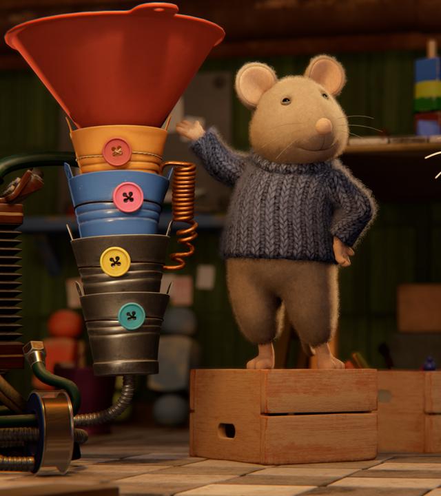 Sam steht neben einem für Julia selbtgebastelten Musikinstrument und präsentiert es stolz. Es besteht aus bunten, ineinandergefügten Eimern und einem großen, roten Trichter obenauf und sieht aus wie eine Riesen-Tuba.