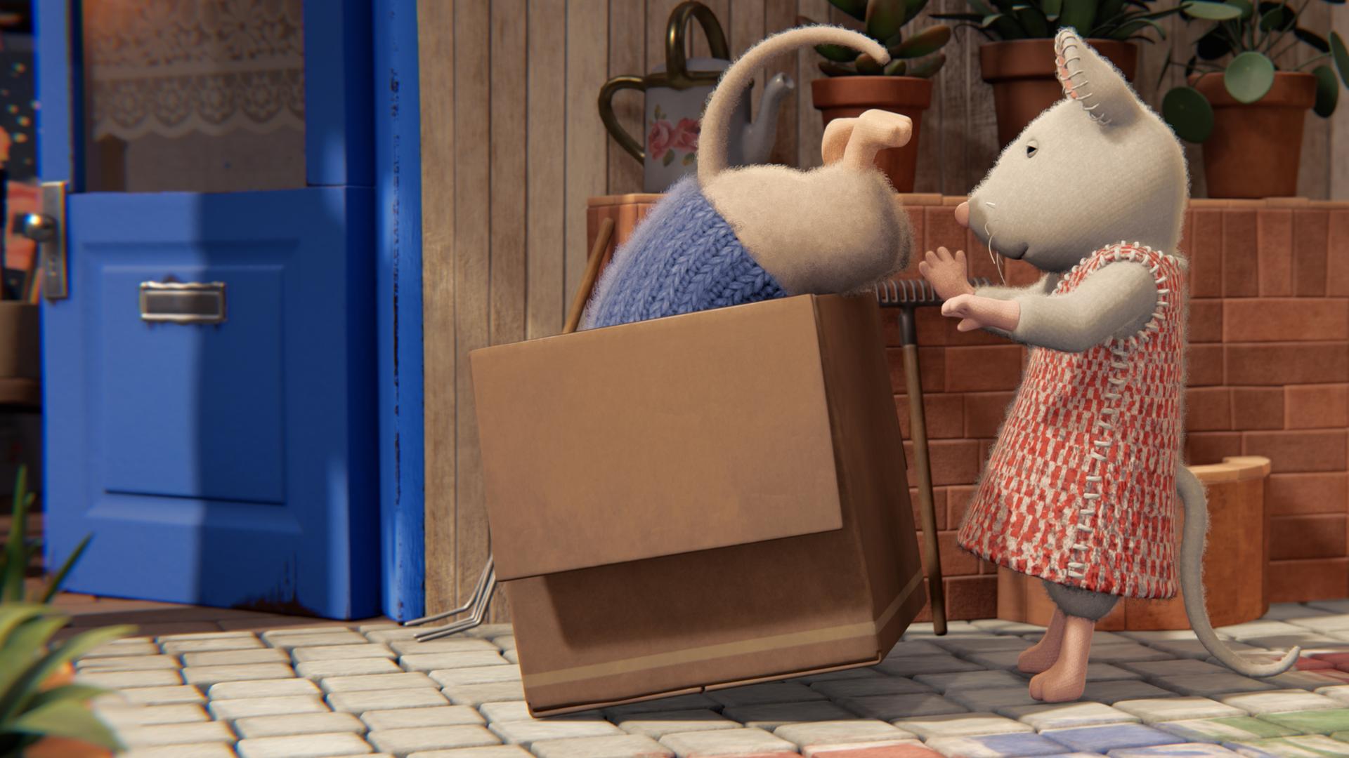 Julia hilft Sam, sich in einem Karton zu verstecken. Sam ist schon mit dem Oberkörper darin verschwunden. Nur sein Hinterteil mit dem Mäuseschwanz schaut noch heraus.