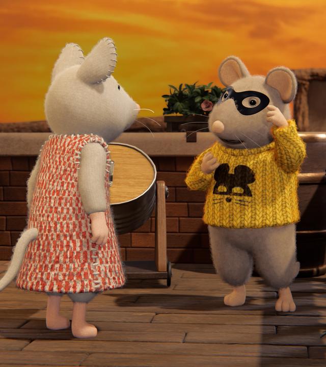 Julia steht auf der Dachterrasse mit einer Maus in gelbem Pulli und schwarzer Maske. Der Himmel leuchtet orange-gelb.