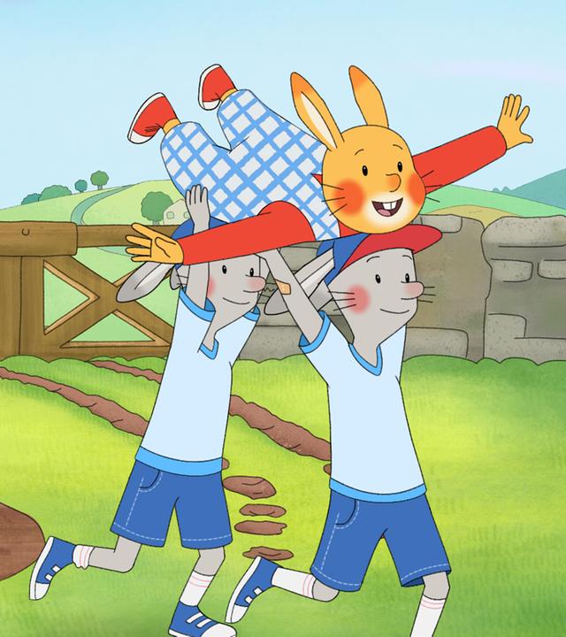 Die Zwillinge Friedrich und Wilhelm tragen über ihren Köpfen Karlchen auf ihren Händen und rennen in einem Garten umher. Karlchen hat die Arme wie ein Flugzeug ausgebreitet.