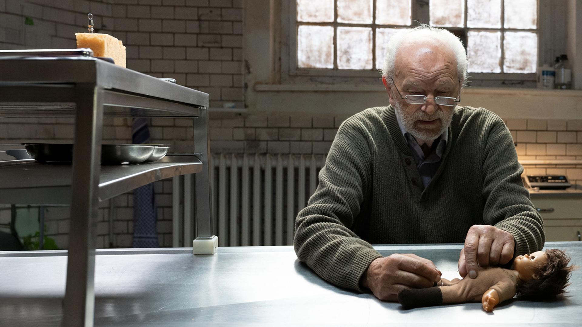 Pathologe Peter simuliert an einer Kinderpuppe eine pathologische Untersuchung. 