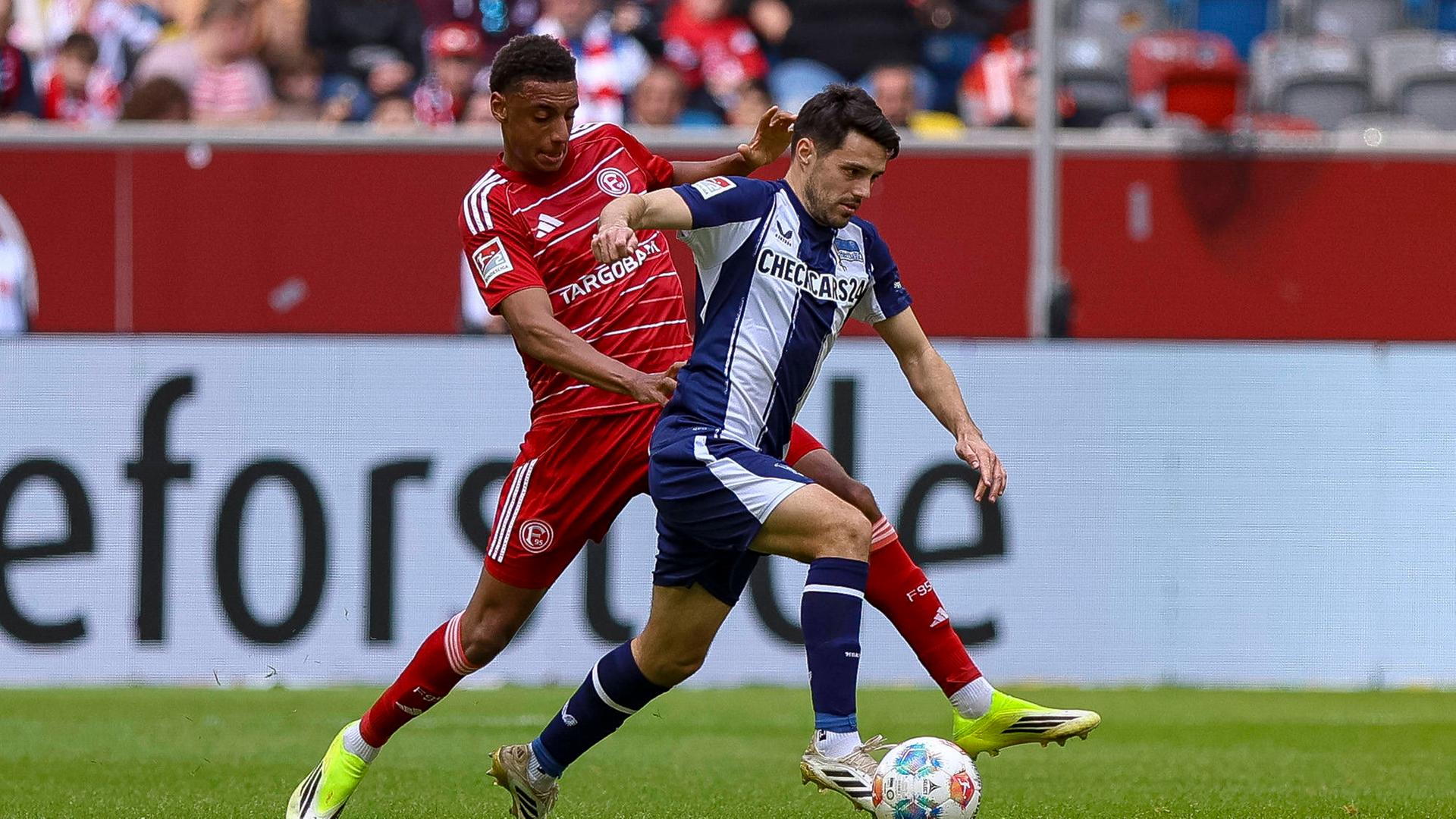 Spieler von Fortuna Düsseldorf und Hertha BSC kämpfen. 