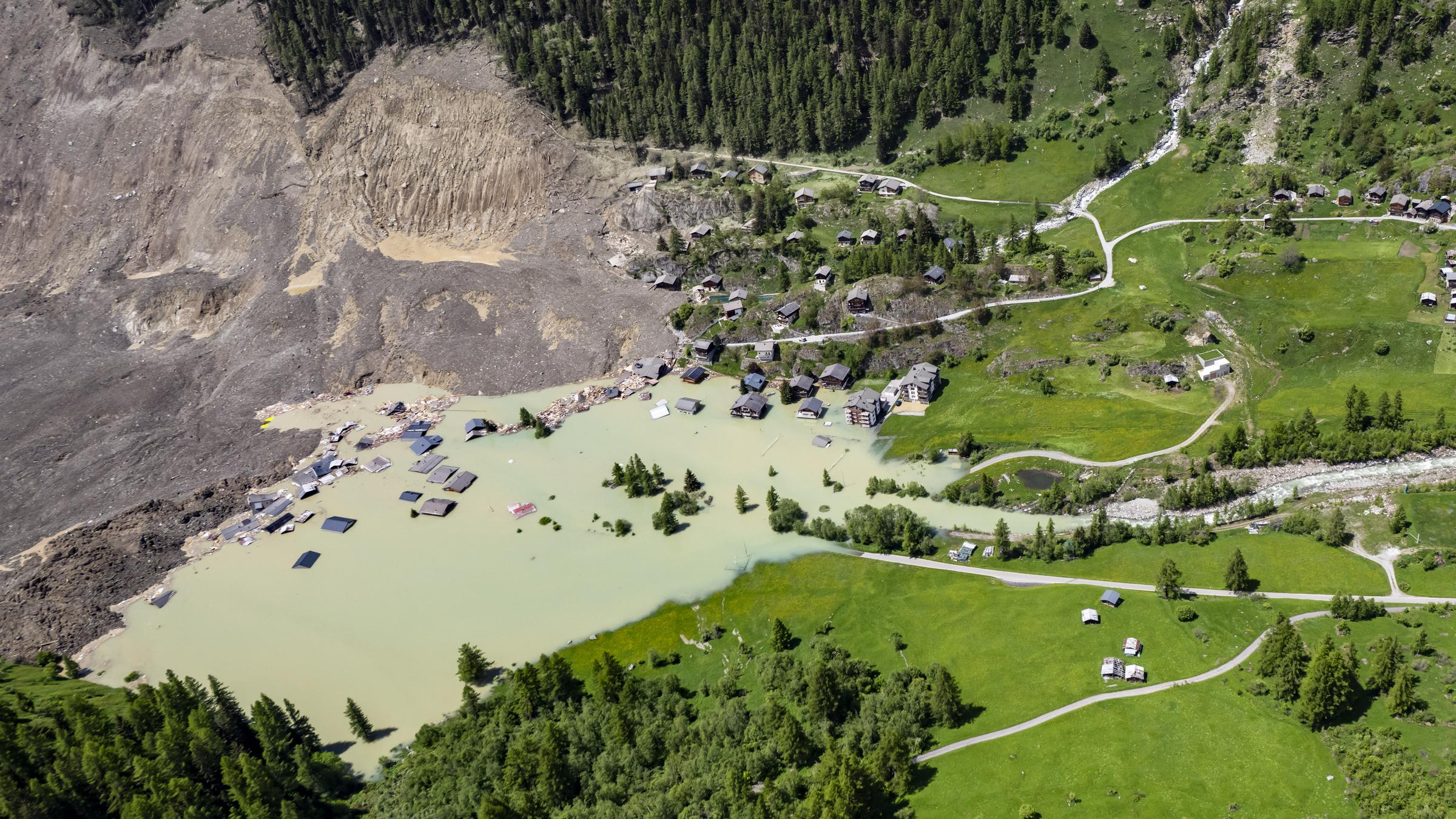  "Trügerische Alpenidylle - Was tun, wenn Berge wegbrechen?": Totale: Ein Tal in den Alpen ist von Geröllmassen überlagert. Im aufgestauten Wasser sind noch Dächer von überfluteten Häusern zu sehen