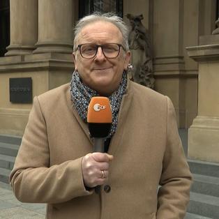 ZDF-Reporter Frank Bethamnn mit Mikro vor der Fraankfurter Börse. 