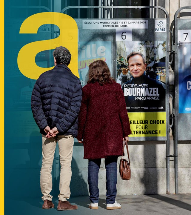 Ein Mann und eine Frau stehen vor den Wahlplakaten in einer französischen Stadt Villers-Cotterêts