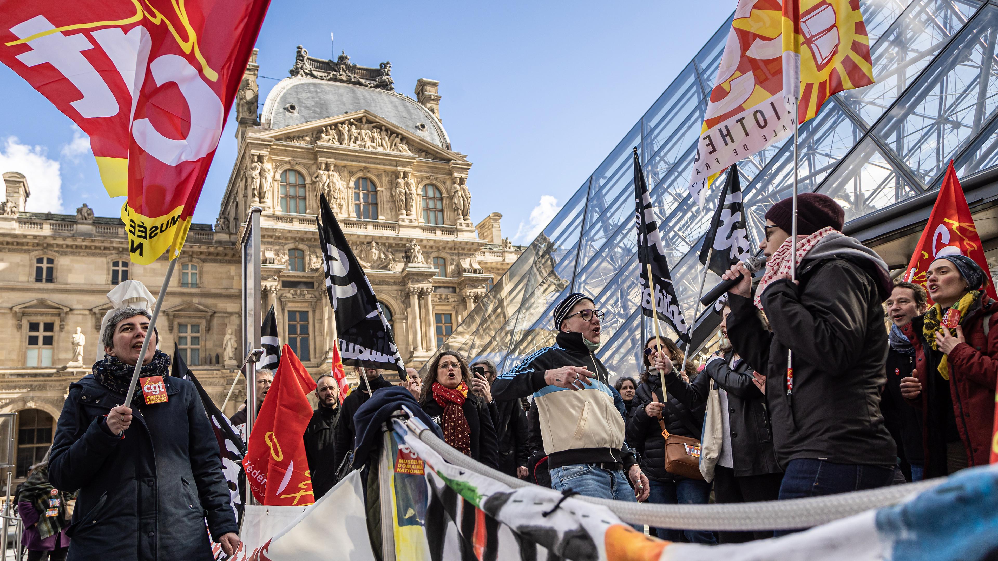 Angestellte des Louvre-Museums blockieren den Eingang des Museums während einer Demonstration vor der Louvre-Pyramide, aufgenommen am 27.03.2023