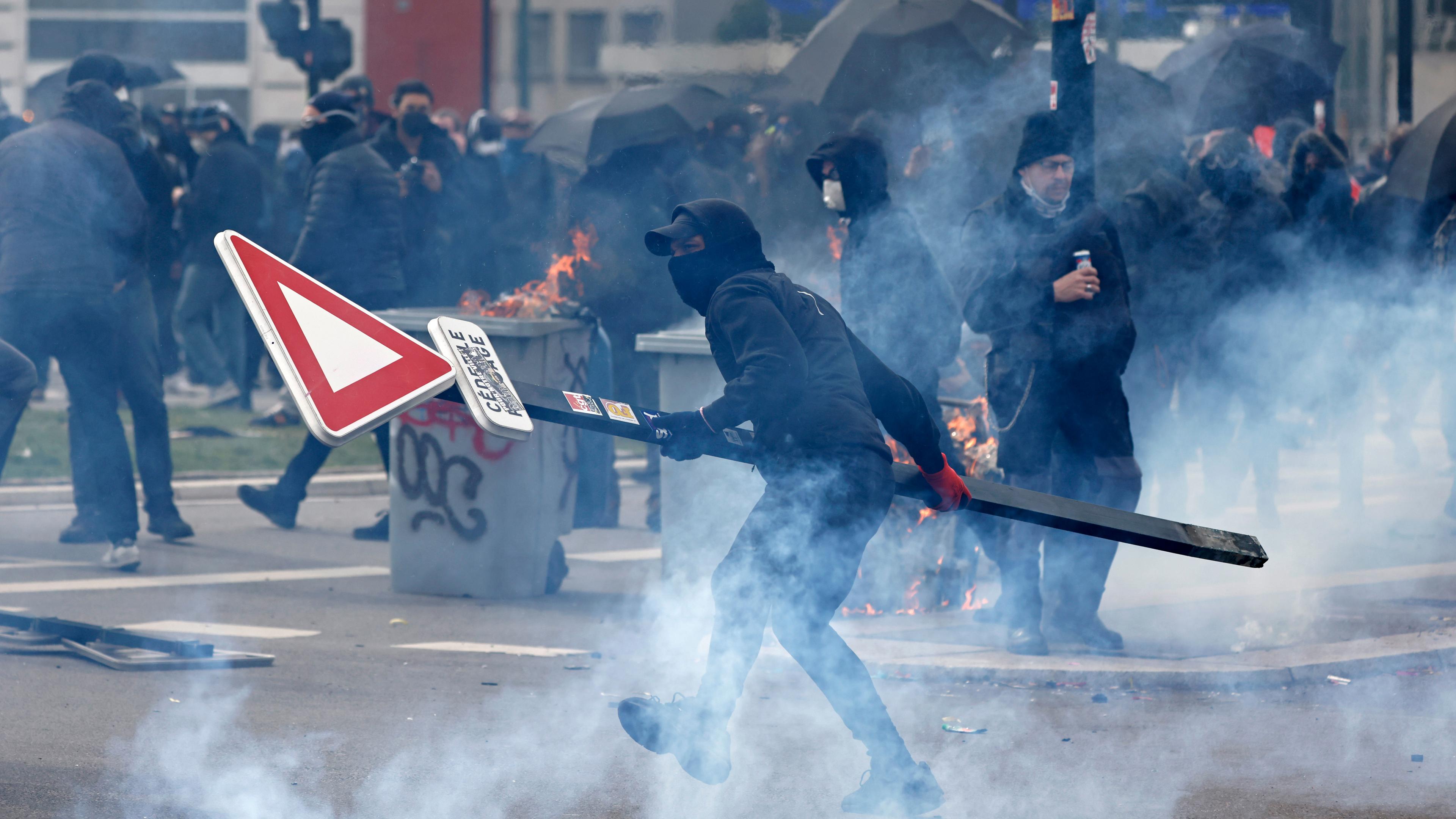 Ein Jugendlicher wirft ein Straßenschild bei Zusammenstößen im Rahmen einer Demonstration, aufgenommen am 28.03.2023 in Nantes (Frankreich)