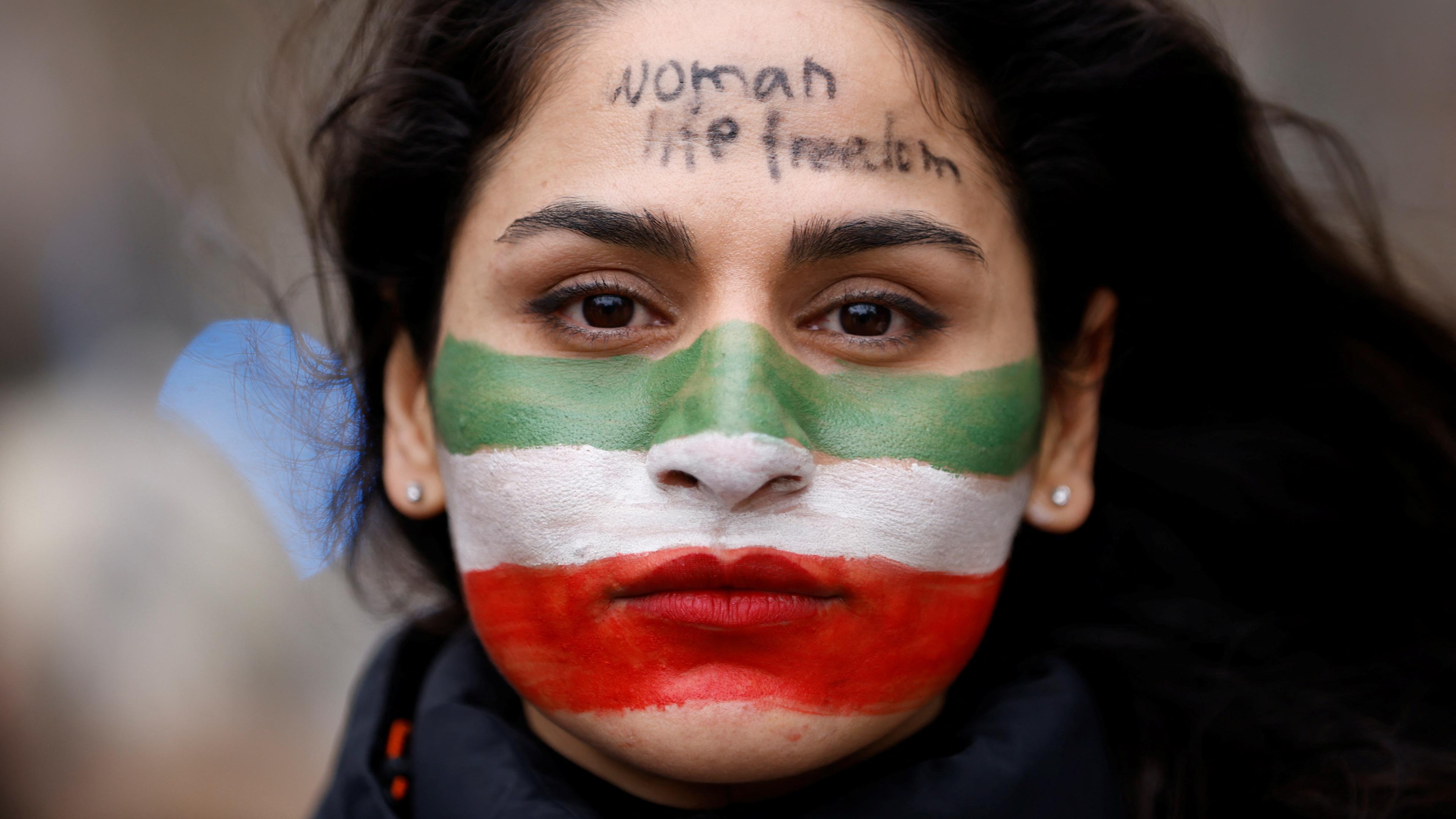 A woman with her face painted in the colors of the Iranian flag