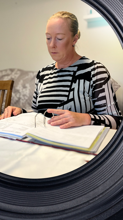 Mandy Mewes sitzt am Tisch, vor ihr liegt ein Ordner mit Rechnungen.