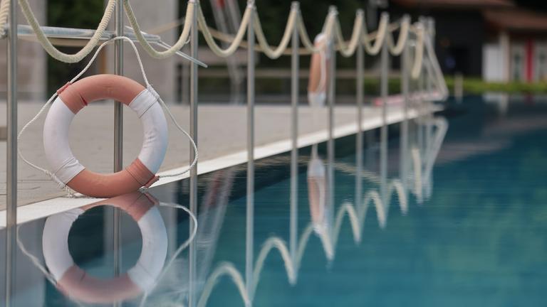 06.07.2025, Baden-Württemberg, Sigmaringen: Ein Rettungsring spiegelt sich in der Wasseroberfläche in einem Freibad