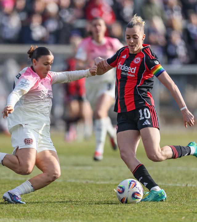 Leverkusens Außenverteidigerin Estrella Merino Gonzalez grätscht im Zweikampf mit Frankfurts Mittelfeldspielerin Laura Freigang in Richtung Ball