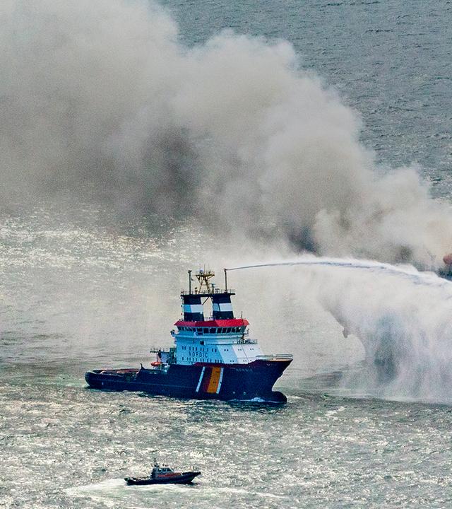 Zu sehen ist ein Boot, das versucht das Frachtschiff zu löschen. 