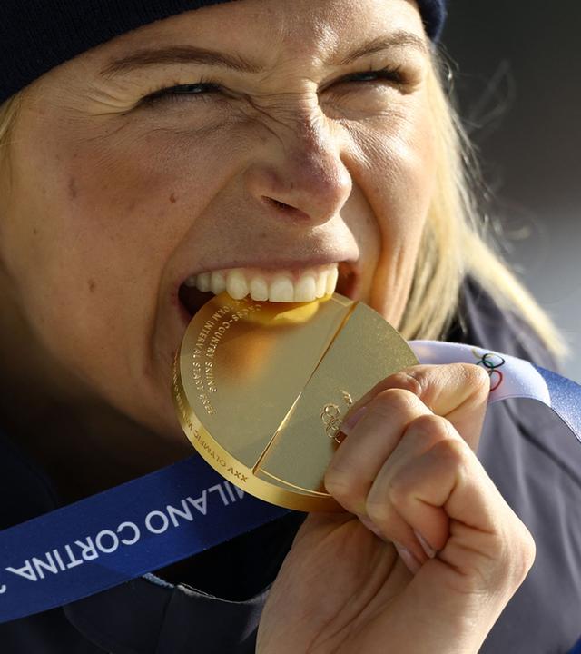 Die schwedische Goldmedaillengewinnerin Frida Karlsson beißt in ihre Medaille am 12.02.2026 in Tesero. 