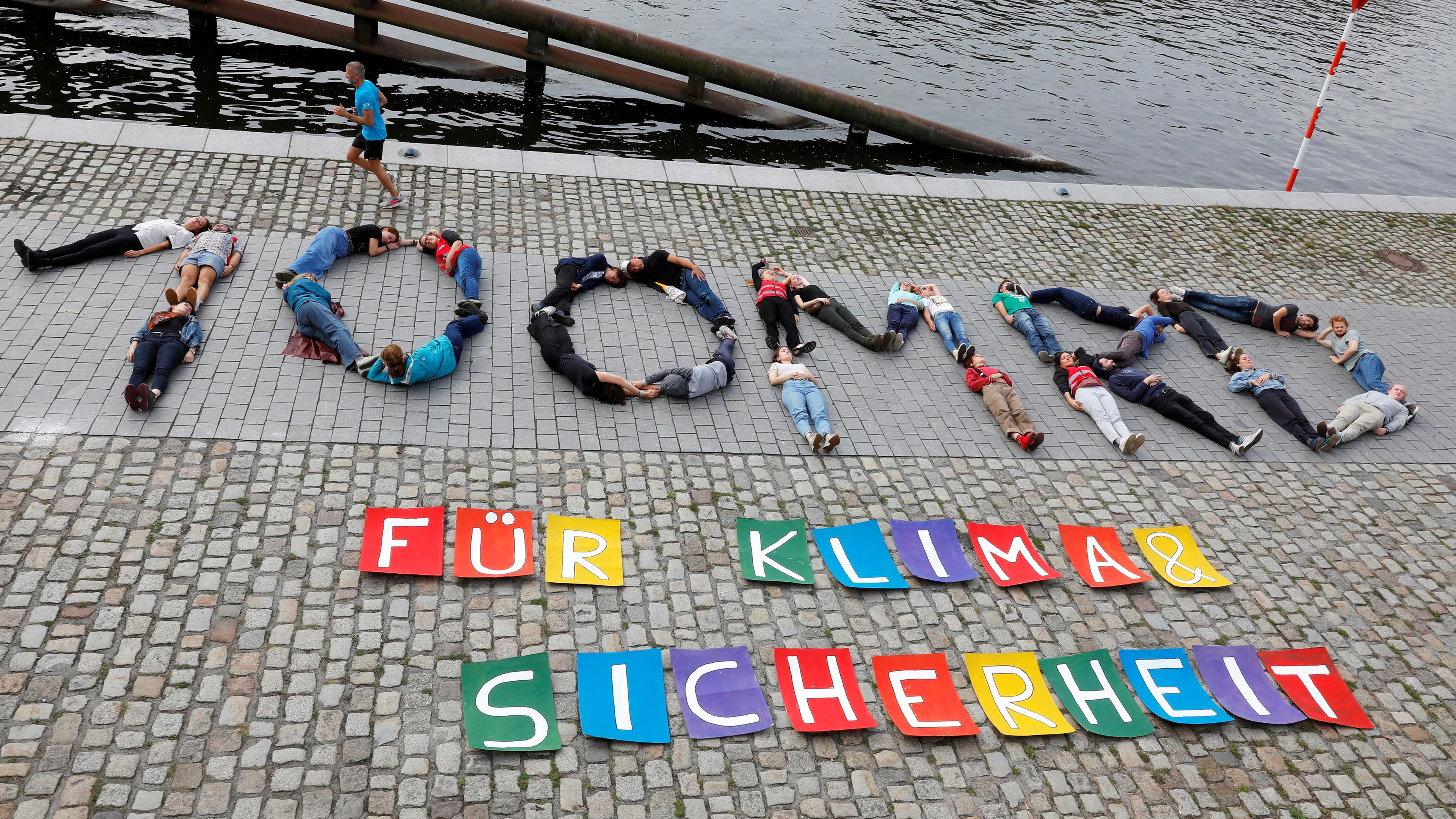 Berlin: "100 Mrd. für Klima und Sicherheit" schreiben Klimaaktivisten von fridays for future auf dem Boden neben die Spree.