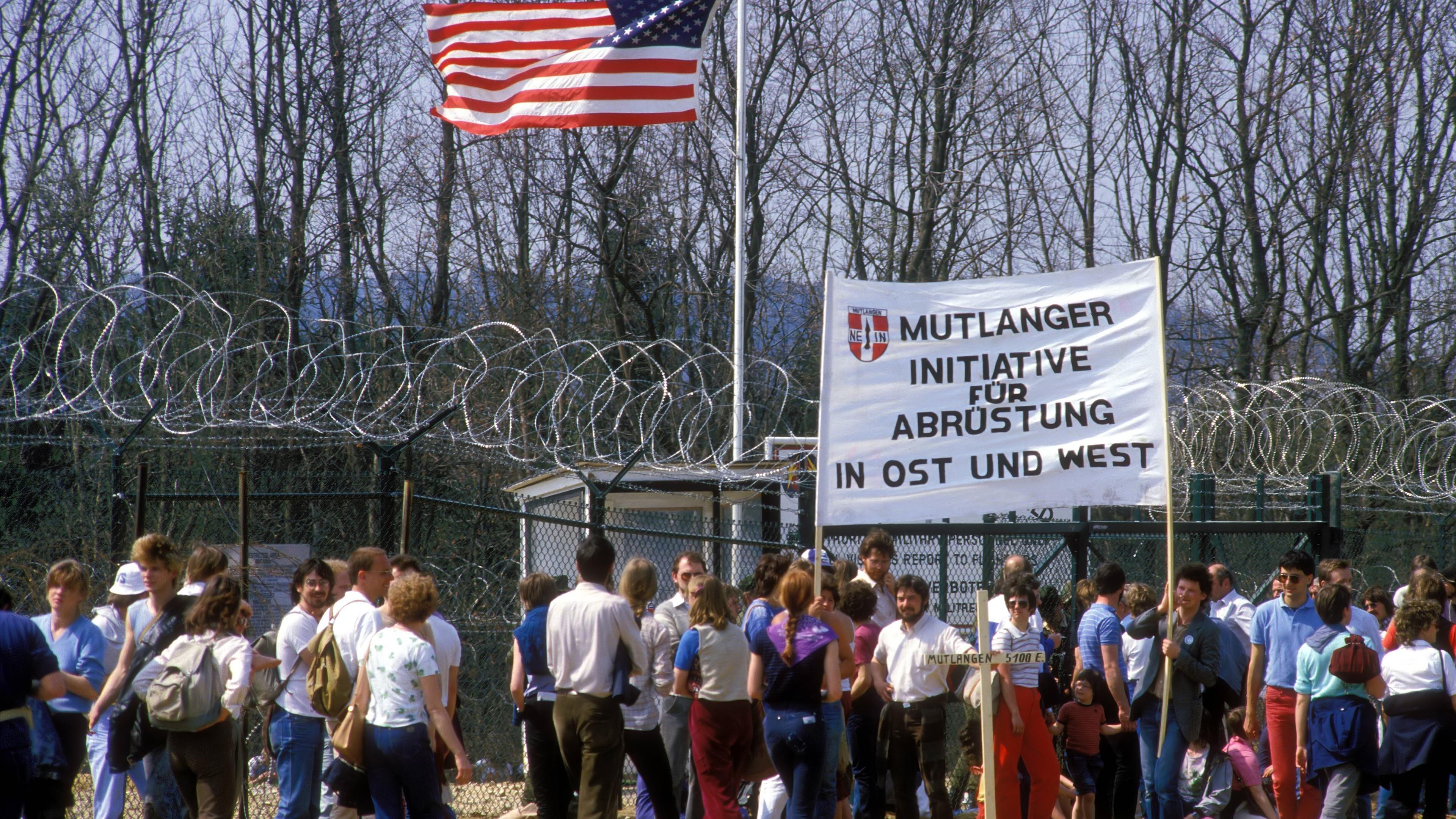 Menschen demonstrieren vor dem US-amerikanischen Militärstützpunkt in Mutlangen mit einem großen Plakat für Abrüstung.